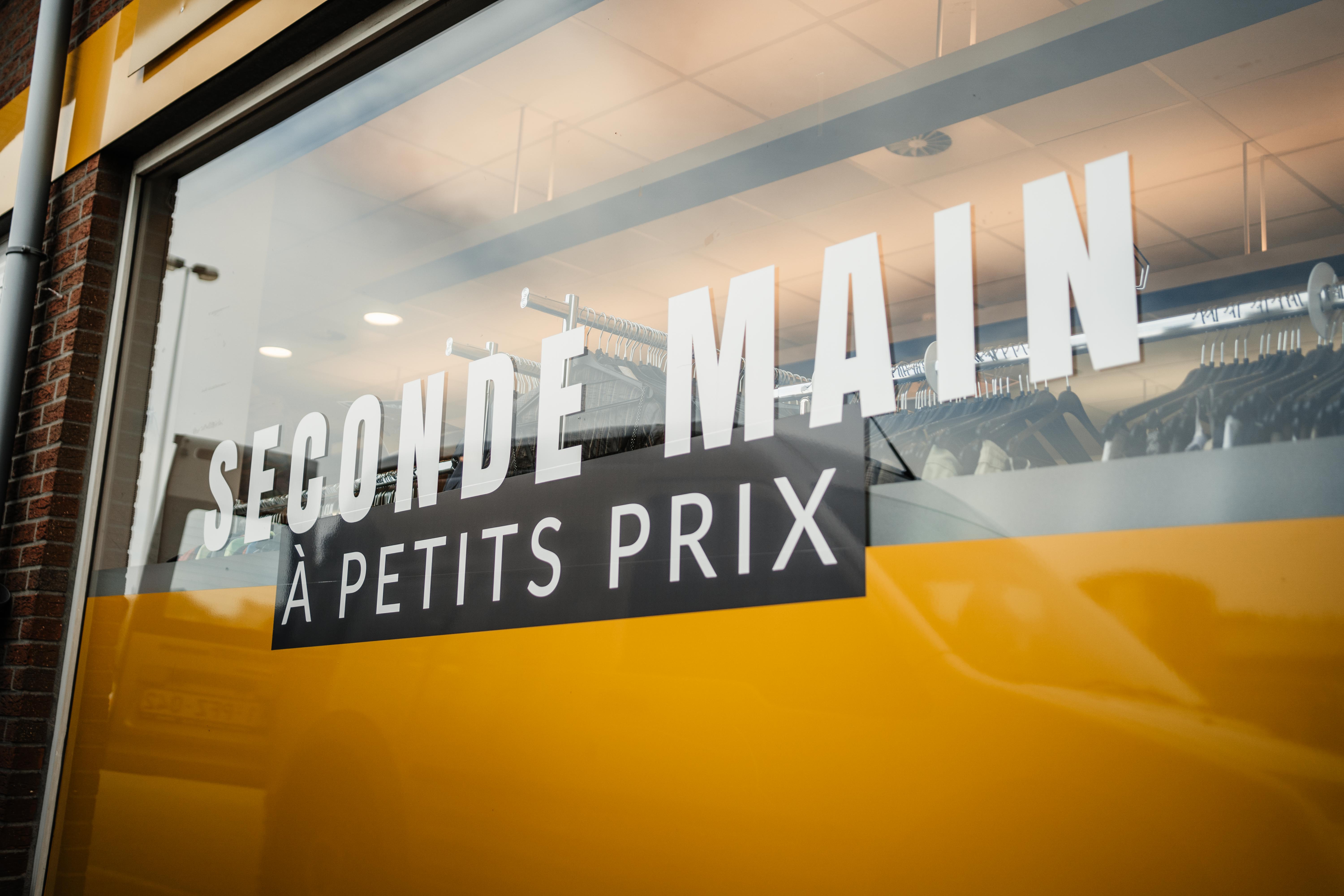 Une enseigne indiquant "seconde main à petits prix", suggérant des articles d'occasion à prix abordables.