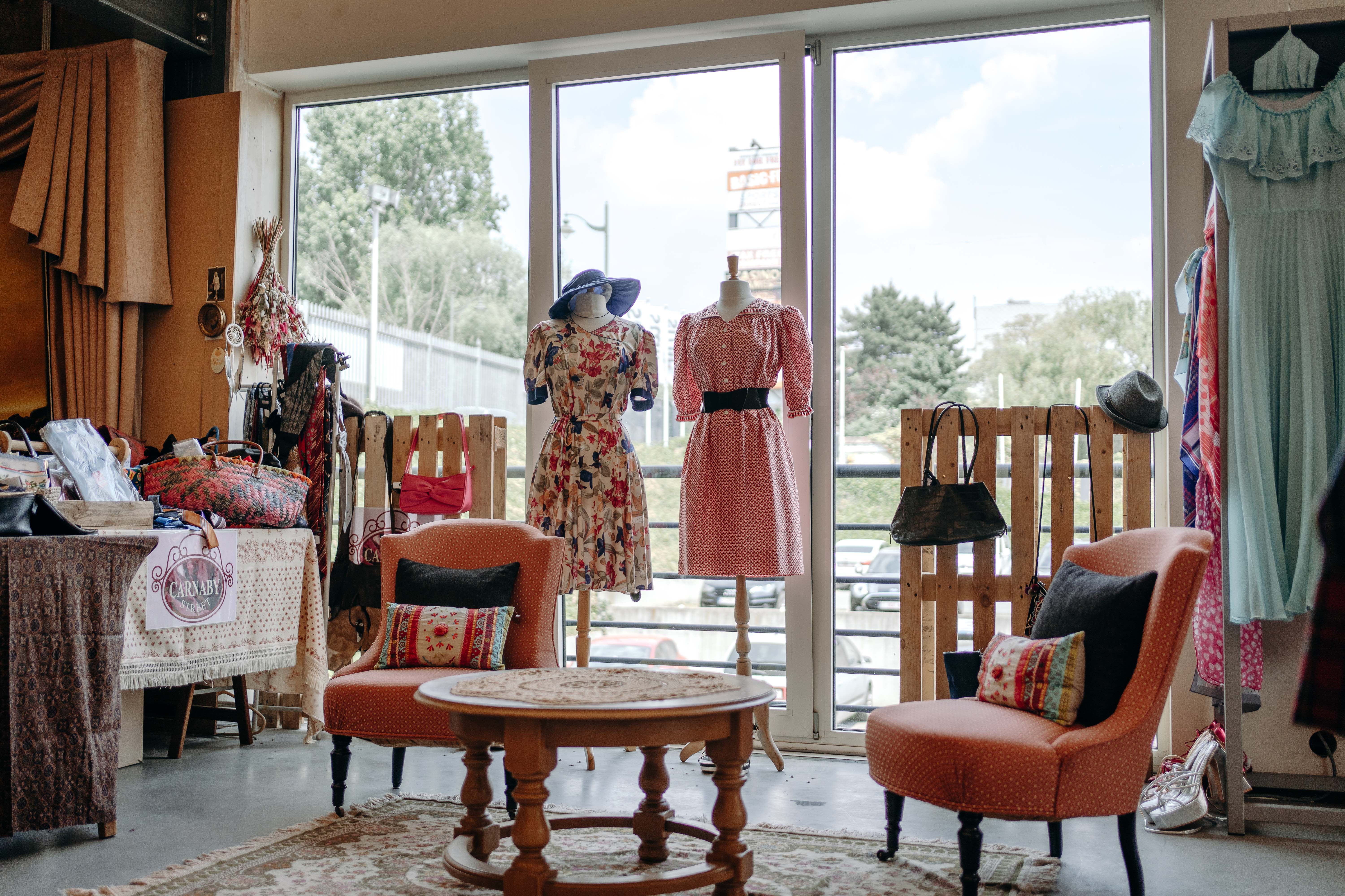 Un magasin rempli de vêtements vintages, soigneusement disposés sur des étagères et des cintres.